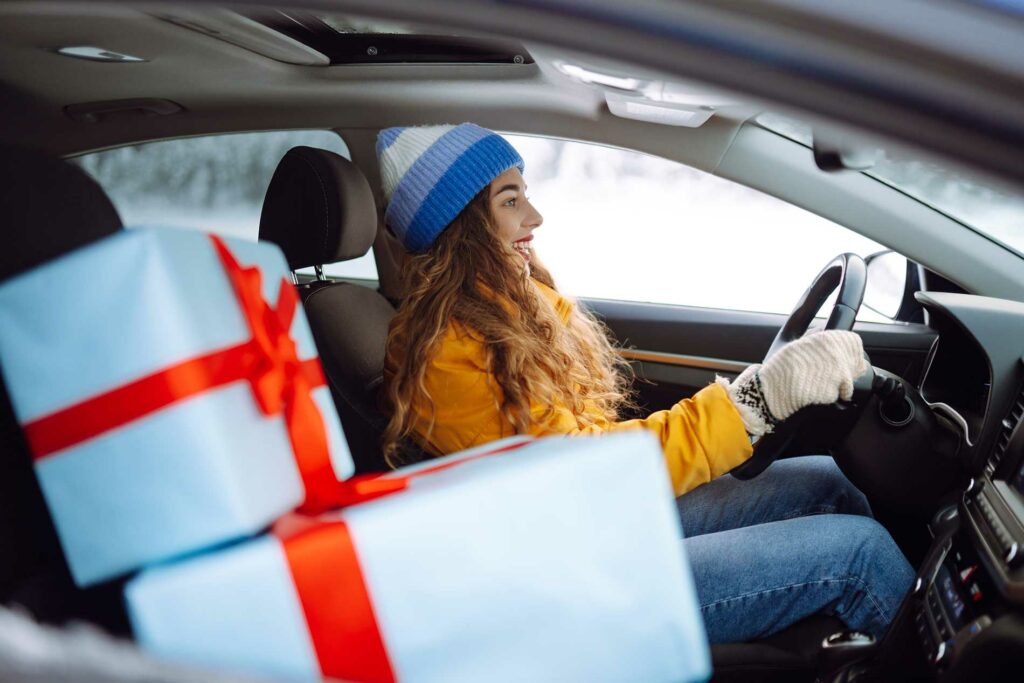 woman driving in a car with gifts